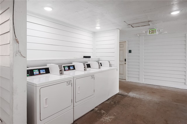 washroom featuring washing machine and clothes dryer and wood walls