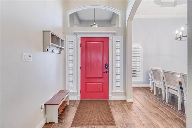 entryway with crown molding, hardwood / wood-style floors, a towering ceiling, and a chandelier