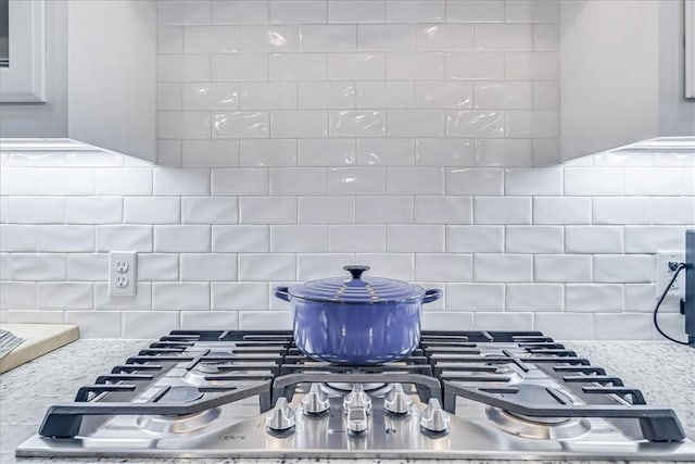 details featuring tasteful backsplash, light stone countertops, and stainless steel gas stovetop