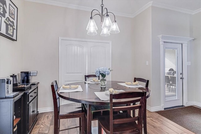 dining area with hardwood / wood-style flooring, an inviting chandelier, and ornamental molding