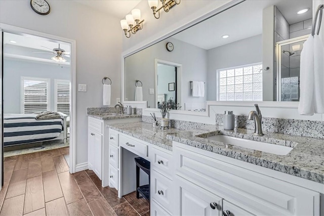 bathroom with a shower with door, vanity, and ceiling fan with notable chandelier