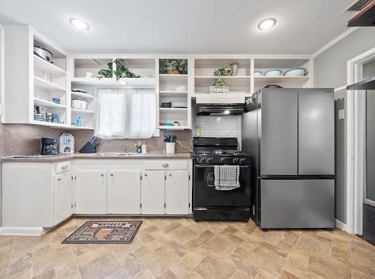 1058 Vaky St, Corpus Christi, TX 78404 - kitchen featuring black gas range, freestanding refrigerator, open shelves, stone finish floors, and white cabinets