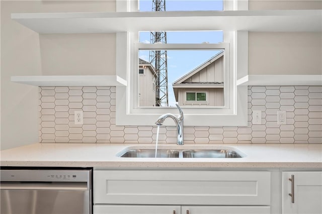 kitchen with backsplash, dishwasher, white cabinetry, and a sink