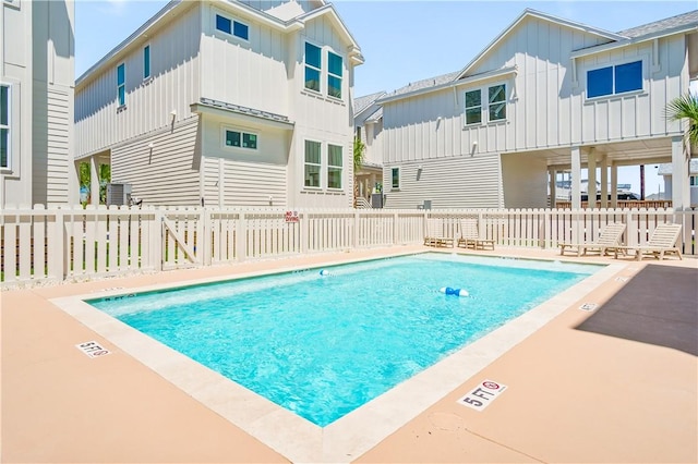 community pool with a patio area, central AC unit, and fence