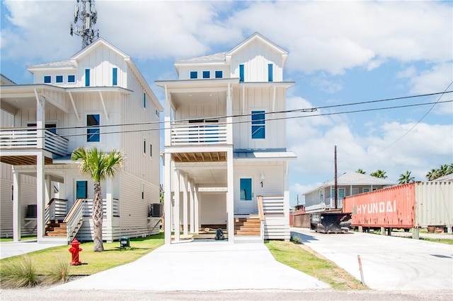 beach home featuring a standing seam roof, cooling unit, board and batten siding, and driveway