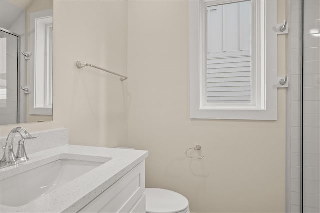 bathroom featuring vanity, toilet, and a shower with door