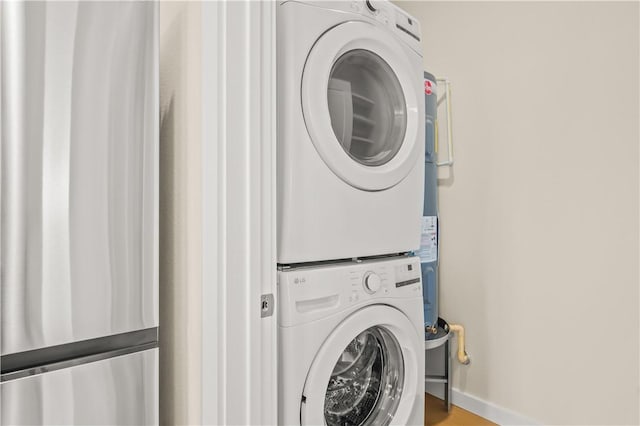 laundry area with baseboards and stacked washing maching and dryer