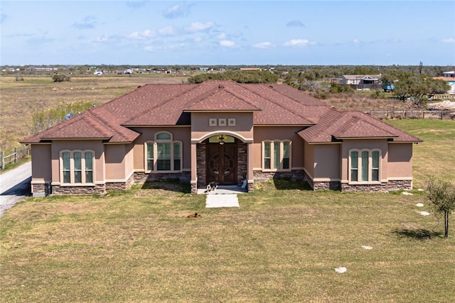 mediterranean / spanish home with stone siding, stucco siding, and a front lawn