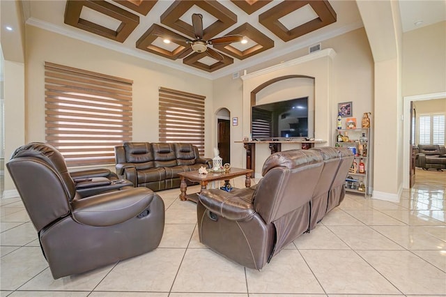 living room featuring light tile patterned floors, a ceiling fan, coffered ceiling, arched walkways, and a towering ceiling