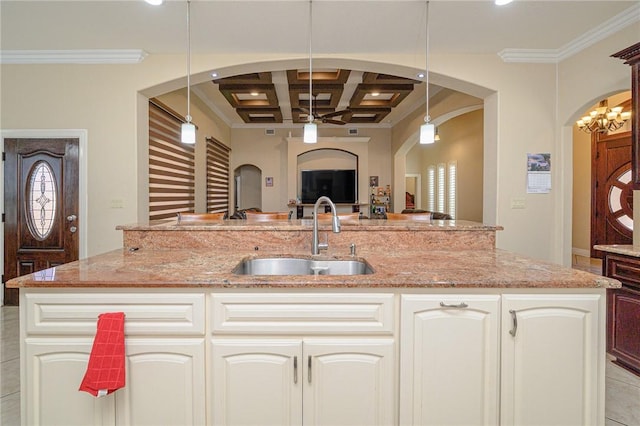 kitchen with light stone countertops, coffered ceiling, arched walkways, a sink, and open floor plan