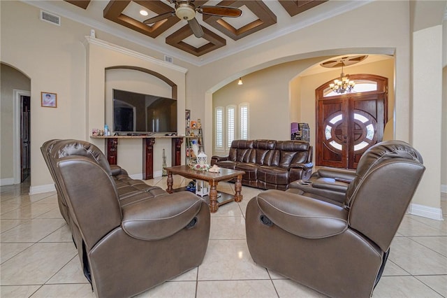 living area featuring ceiling fan with notable chandelier, visible vents, arched walkways, and coffered ceiling