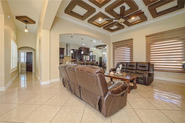 living room with light tile patterned floors, arched walkways, a towering ceiling, and a ceiling fan