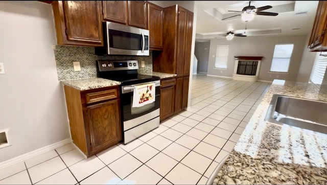 kitchen featuring decorative backsplash, appliances with stainless steel finishes, light stone counters, ceiling fan, and light tile patterned flooring