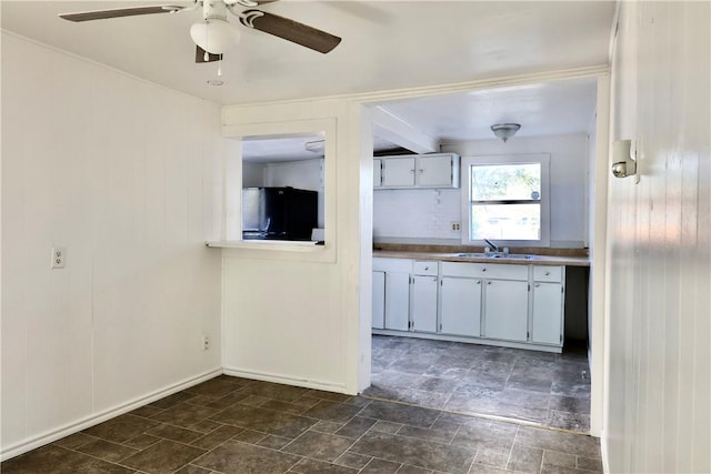 kitchen featuring white cabinets, ceiling fan, black refrigerator, and sink