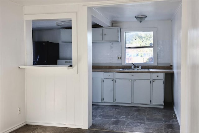 kitchen featuring backsplash, black refrigerator, and sink