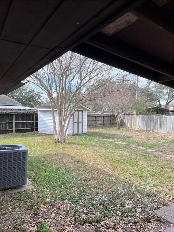 view of yard with an outbuilding, a shed, a fenced backyard, and cooling unit