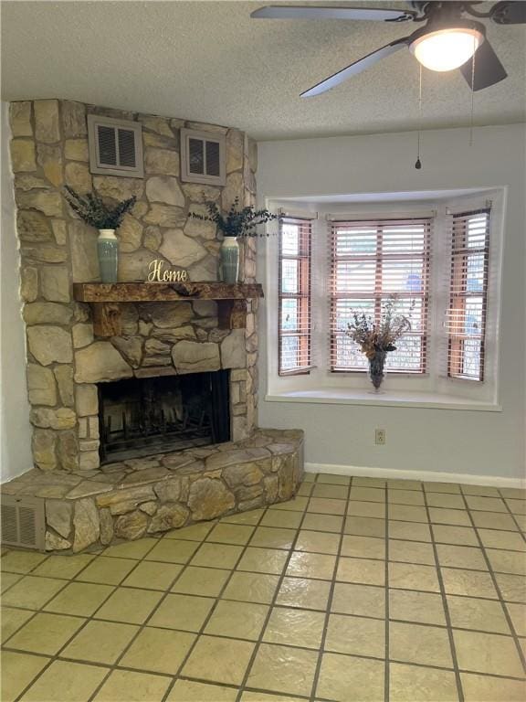 unfurnished living room with light tile patterned floors, visible vents, a textured ceiling, and a stone fireplace