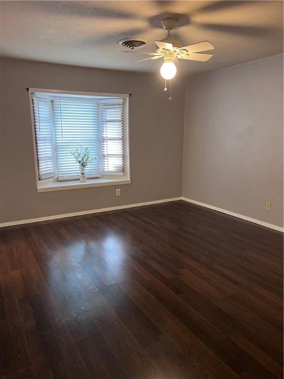 spare room featuring ceiling fan, baseboards, visible vents, and dark wood finished floors