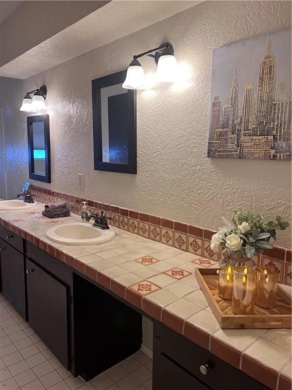 bathroom featuring a textured wall, a textured ceiling, a sink, and double vanity