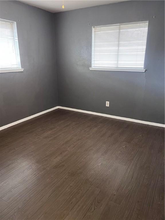 unfurnished room with dark wood-style flooring and baseboards