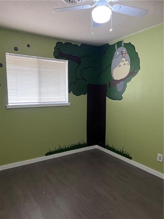 empty room featuring ceiling fan, baseboards, and wood finished floors