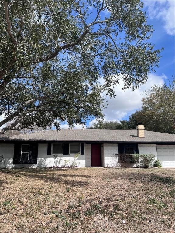 single story home featuring a garage, a chimney, and a front yard