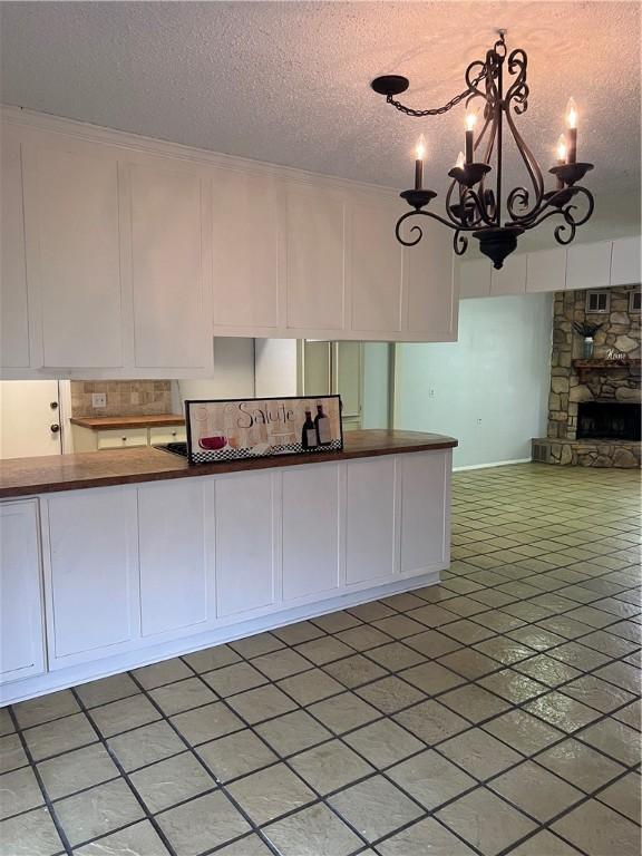 kitchen featuring a fireplace, white cabinets, and a textured ceiling