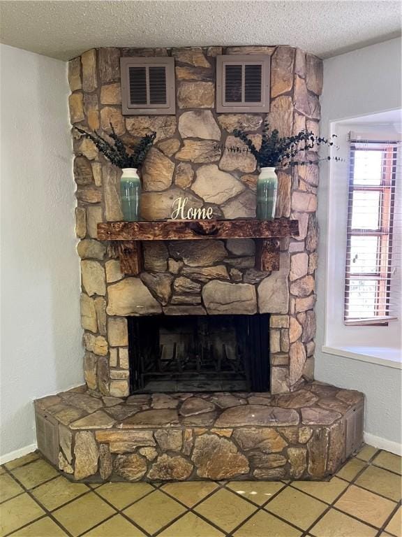 details featuring visible vents, a fireplace, a textured ceiling, and baseboards