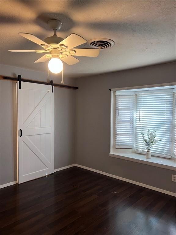 spare room featuring dark wood-style flooring, visible vents, and baseboards