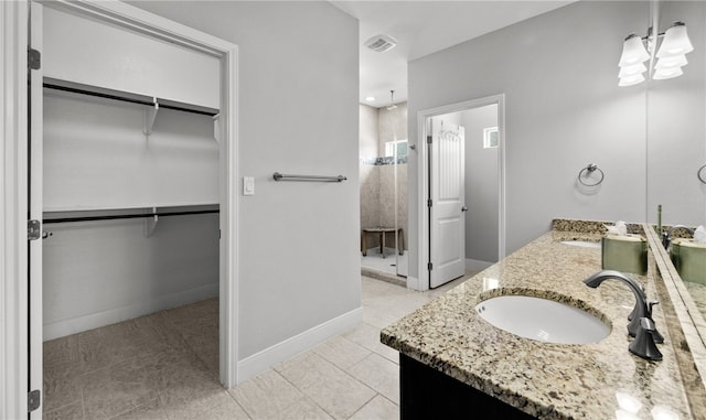 bathroom with tile patterned flooring, vanity, and tiled shower