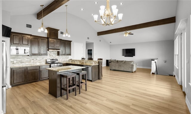 kitchen with a breakfast bar, ceiling fan with notable chandelier, light hardwood / wood-style flooring, appliances with stainless steel finishes, and beamed ceiling