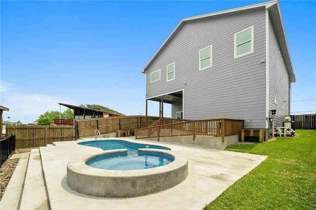 rear view of property with a lawn, an in ground hot tub, and a patio