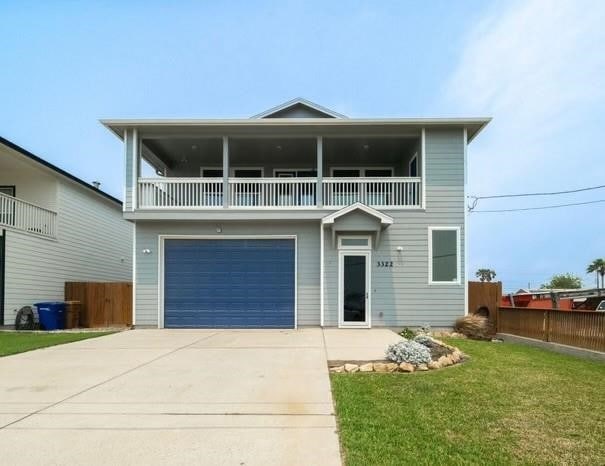 view of front facade featuring a garage, a balcony, and a front lawn