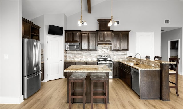 kitchen with a kitchen bar, stainless steel appliances, and light wood-type flooring