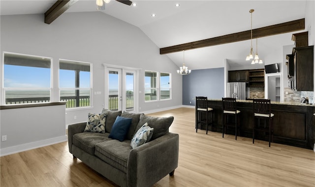 living room featuring ceiling fan with notable chandelier, beam ceiling, light wood-type flooring, and a water view