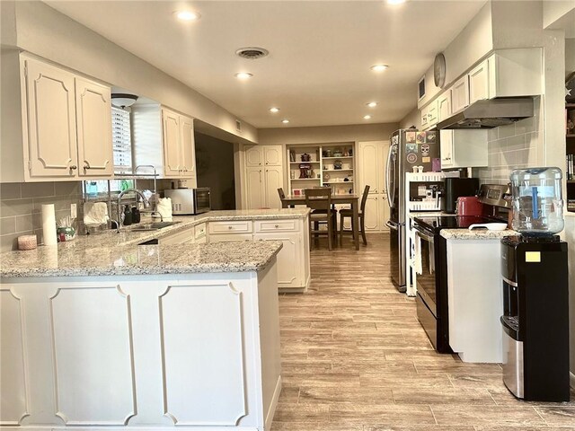 4117 Cork Dr, Corpus Christi, TX 78413 - kitchen featuring black electric range oven, a peninsula, light wood finished floors, white cabinetry, and recessed lighting