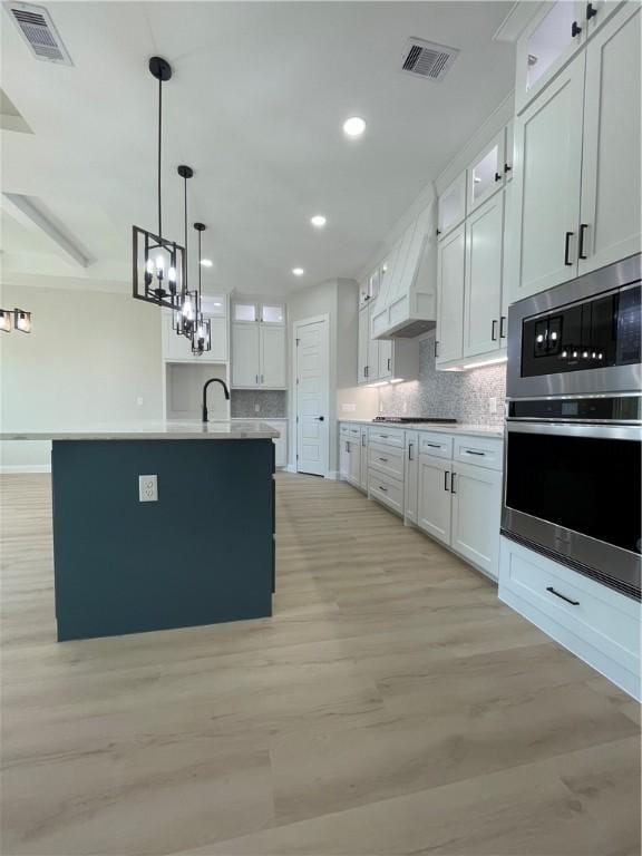 kitchen featuring light wood-style flooring, tasteful backsplash, visible vents, and stainless steel appliances