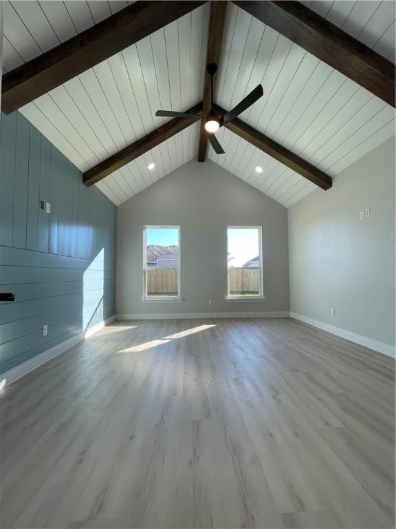 unfurnished living room featuring ceiling fan, baseboards, wood finished floors, and vaulted ceiling with beams