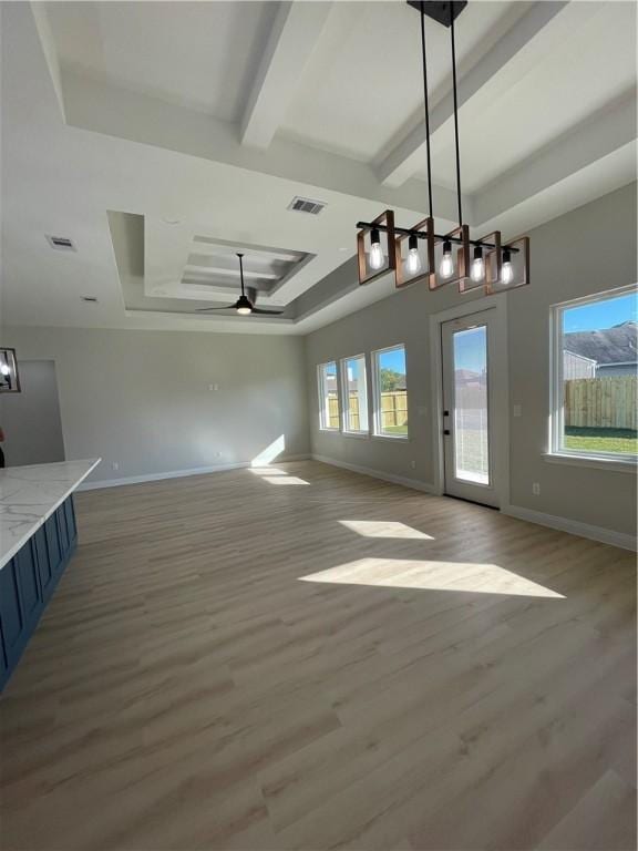 interior space with a tray ceiling, visible vents, beam ceiling, and a wealth of natural light