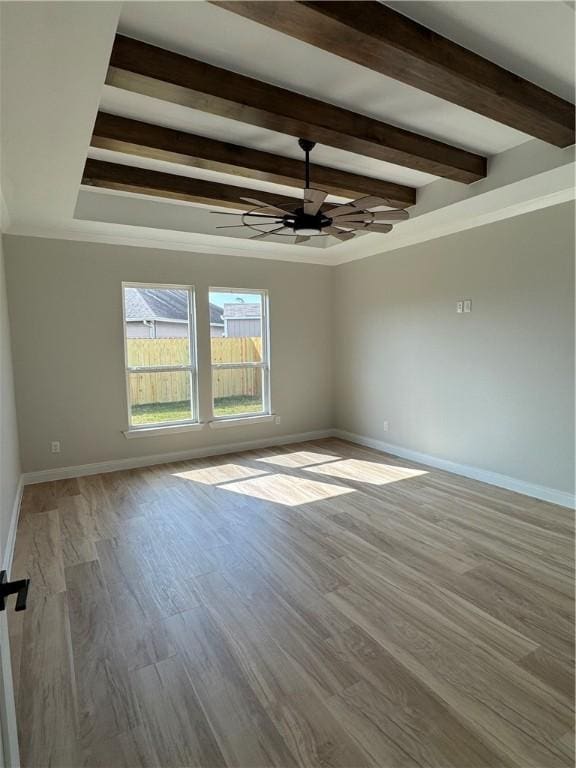 empty room with beam ceiling, wood finished floors, baseboards, and ceiling fan