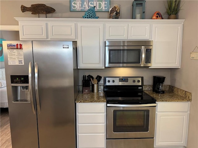 kitchen featuring white cabinetry, appliances with stainless steel finishes, light hardwood / wood-style flooring, and dark stone countertops