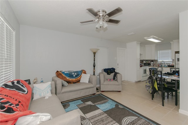 living room featuring light tile patterned floors, ceiling fan, and sink