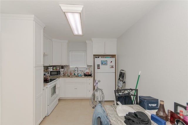 kitchen with white appliances, white cabinetry, and sink