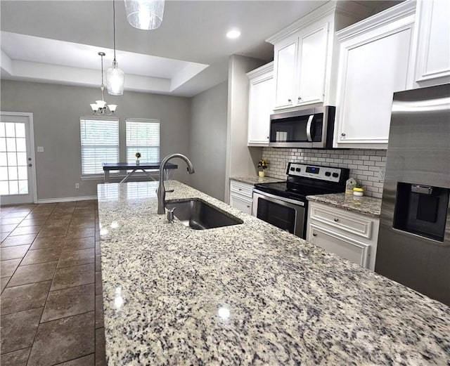 2021 Orange St, Corpus Christi, TX 78418 - kitchen featuring appliances with stainless steel finishes, decorative backsplash, white cabinets, a raised ceiling, and light stone countertops