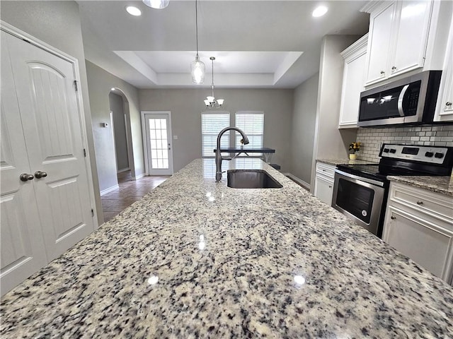 2021 Orange St, Corpus Christi, TX 78418 - kitchen with appliances with stainless steel finishes, arched walkways, decorative backsplash, a raised ceiling, and white cabinetry