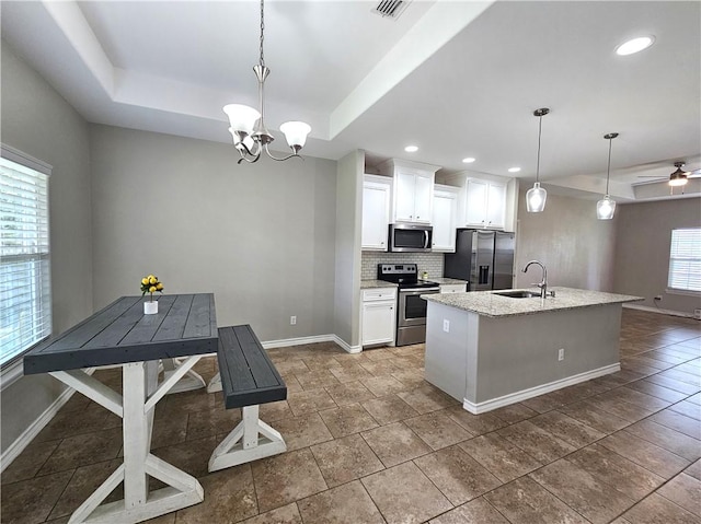 2021 Orange St, Corpus Christi, TX 78418 - kitchen featuring stainless steel appliances, a raised ceiling, decorative backsplash, a kitchen island with sink, and white cabinets
