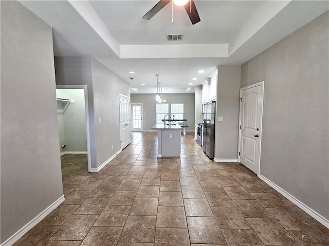 2021 Orange St, Corpus Christi, TX 78418 - kitchen with ceiling fan, white cabinets, a center island with sink, stainless steel refrigerator with ice dispenser, and pendant lighting