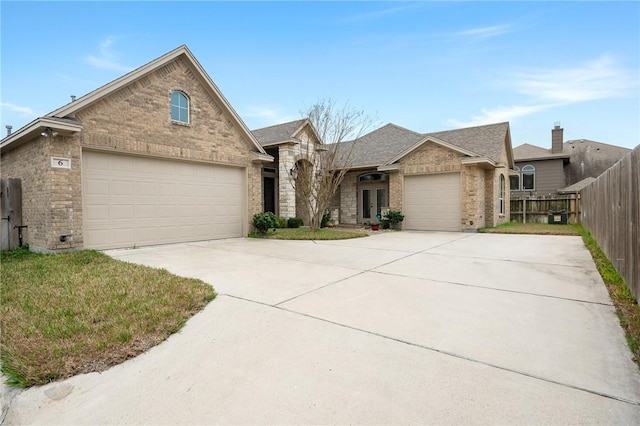 view of front of property with a shingled roof, brick siding, driveway, and fence