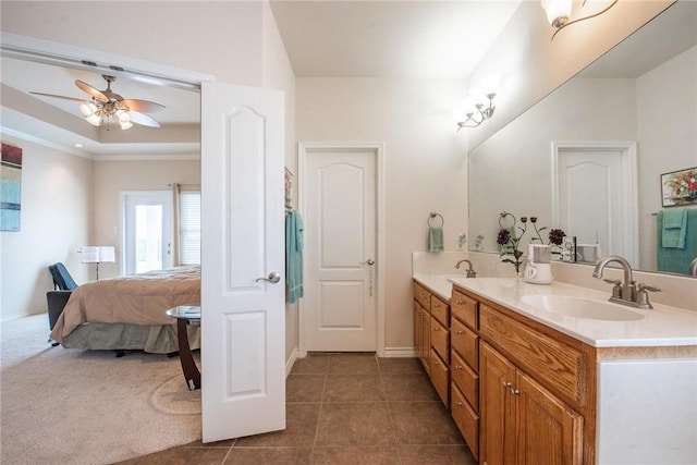 bathroom with double vanity, ensuite bath, a tray ceiling, ceiling fan, and a sink