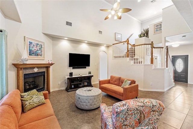 tiled living area with arched walkways, stairs, visible vents, and a ceiling fan